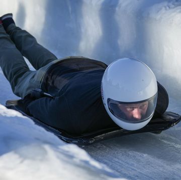 el duque de sussex con casco y sobre una tabla en un tunel de hielo haciendo bobsleigh