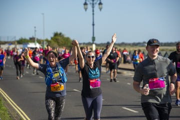 two runners, one wearing a blue backpack and the other in a black shirt, are raising their hands in celebration