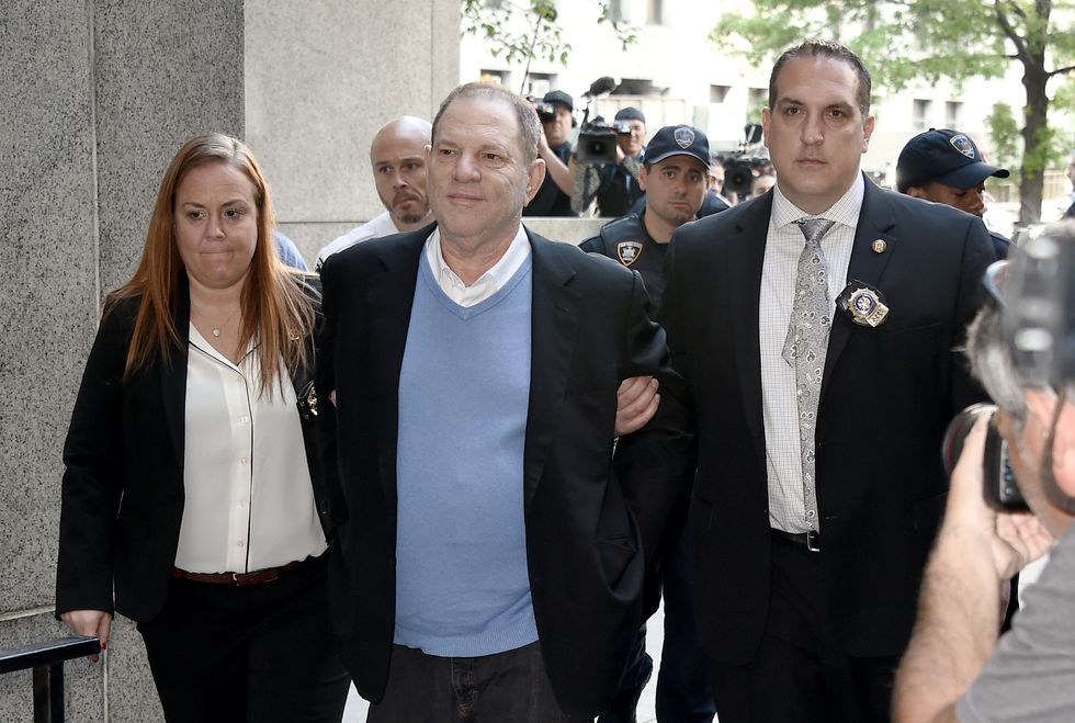 harvey weinstein arriving in court for an arraignment with his arms interlocked with two officials