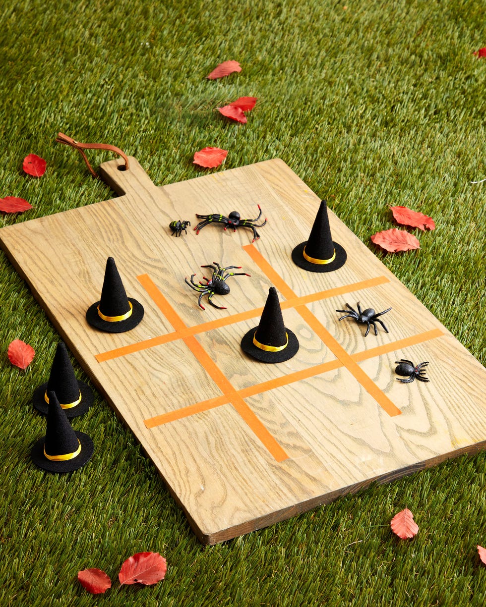 a tic tac toe game made on a wooden cutting board with tape and mini witches hats and plastic spider as the game pieces a tic tac toe game made on a wooden cutting board with tape and mini witches hats and plastic spider as the game pieces