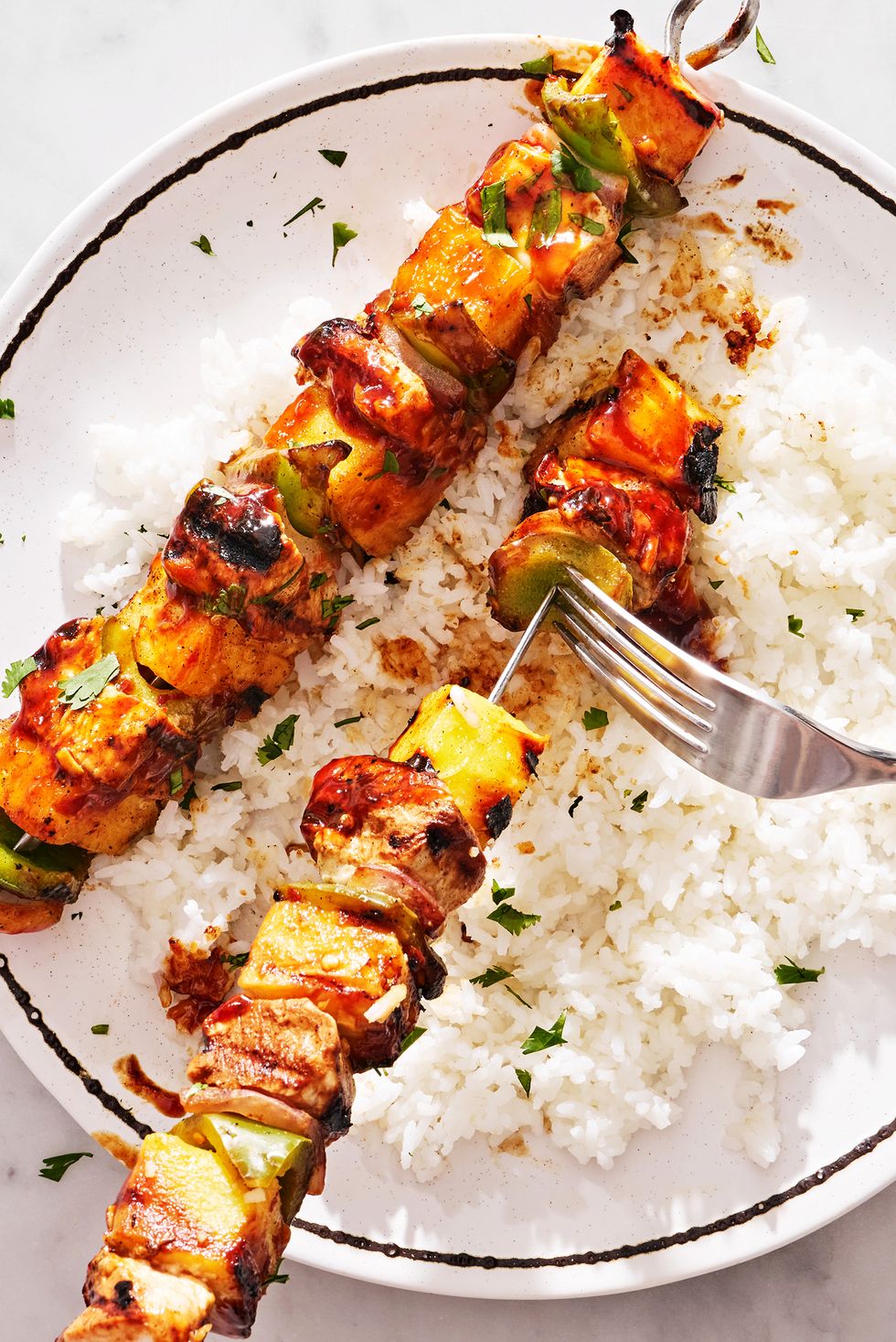 chicken, pineapple, and peppers on a skewer basted with teriyaki