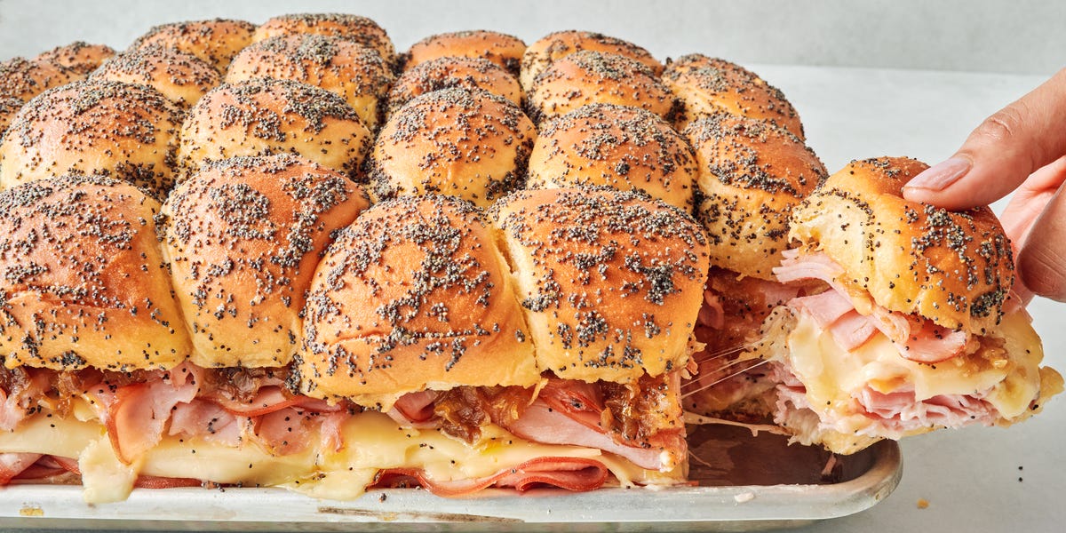 sliders stacked with sliced ham, swiss cheese, honey mustard, caramelized onions all between hawaiian rolls topped with a poppy seed dressing