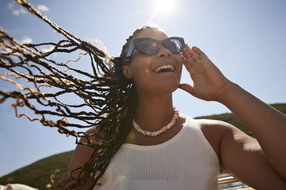 happy woman adjusting sunglasses on sunny day