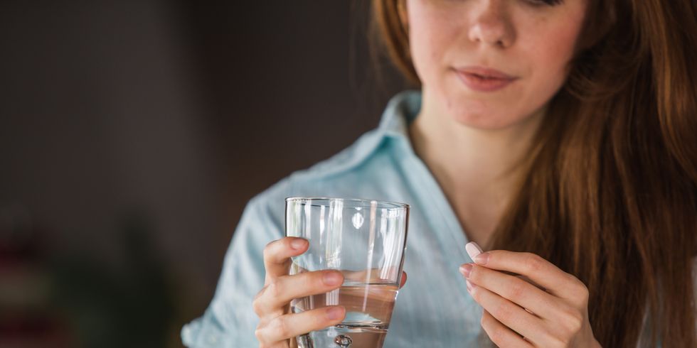 woman holding a glass of water and medication in her hand