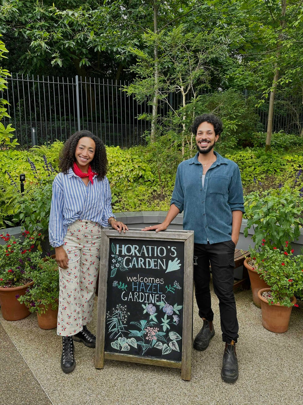 two individuals standing beside a welcoming sign for horatios garden