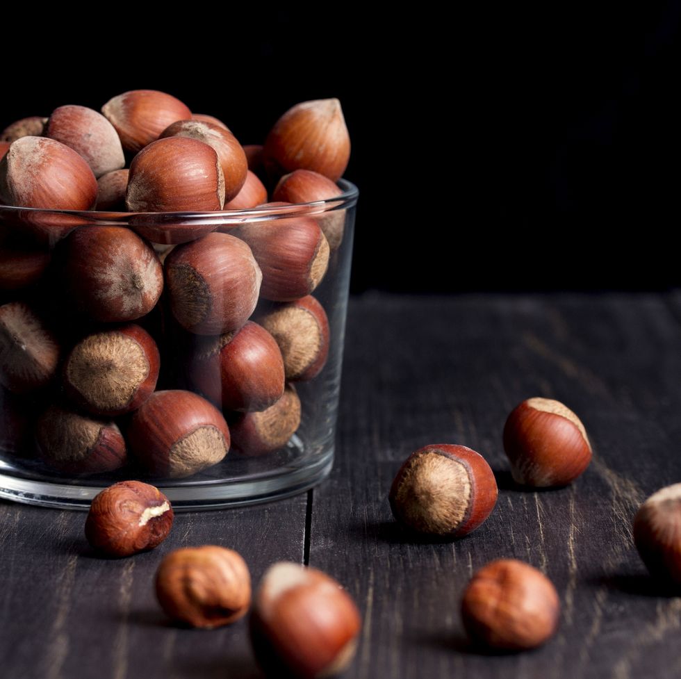 hazelnuts in shell in a transparent vase on a dark wooden table