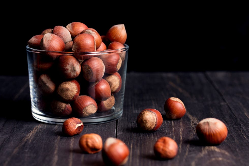 hazelnuts in shell in a transparent vase on a dark wooden table