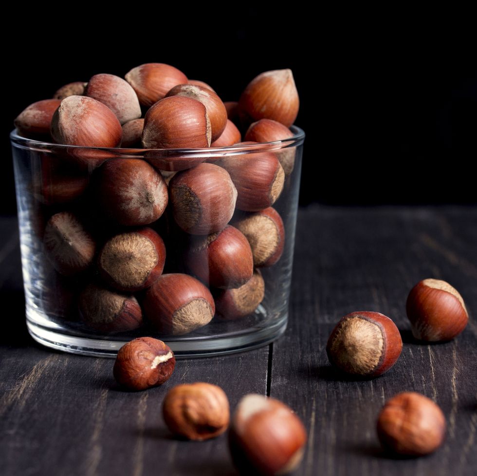 hazelnuts in shell in a transparent vase on a dark wooden table