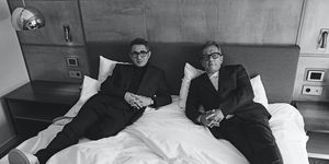 two men sitting on a bed