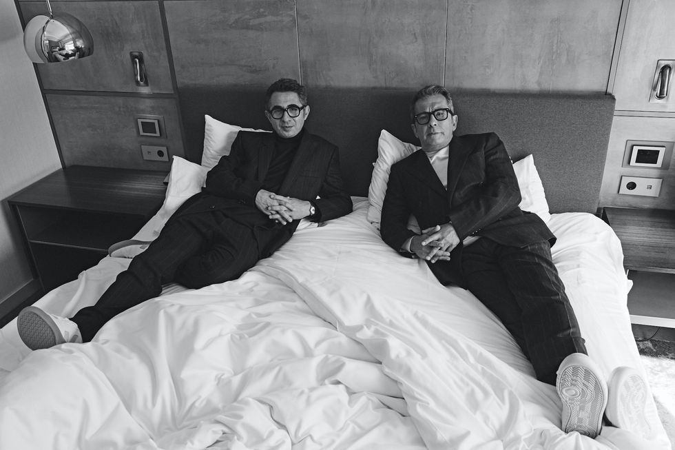 two men sitting on a bed