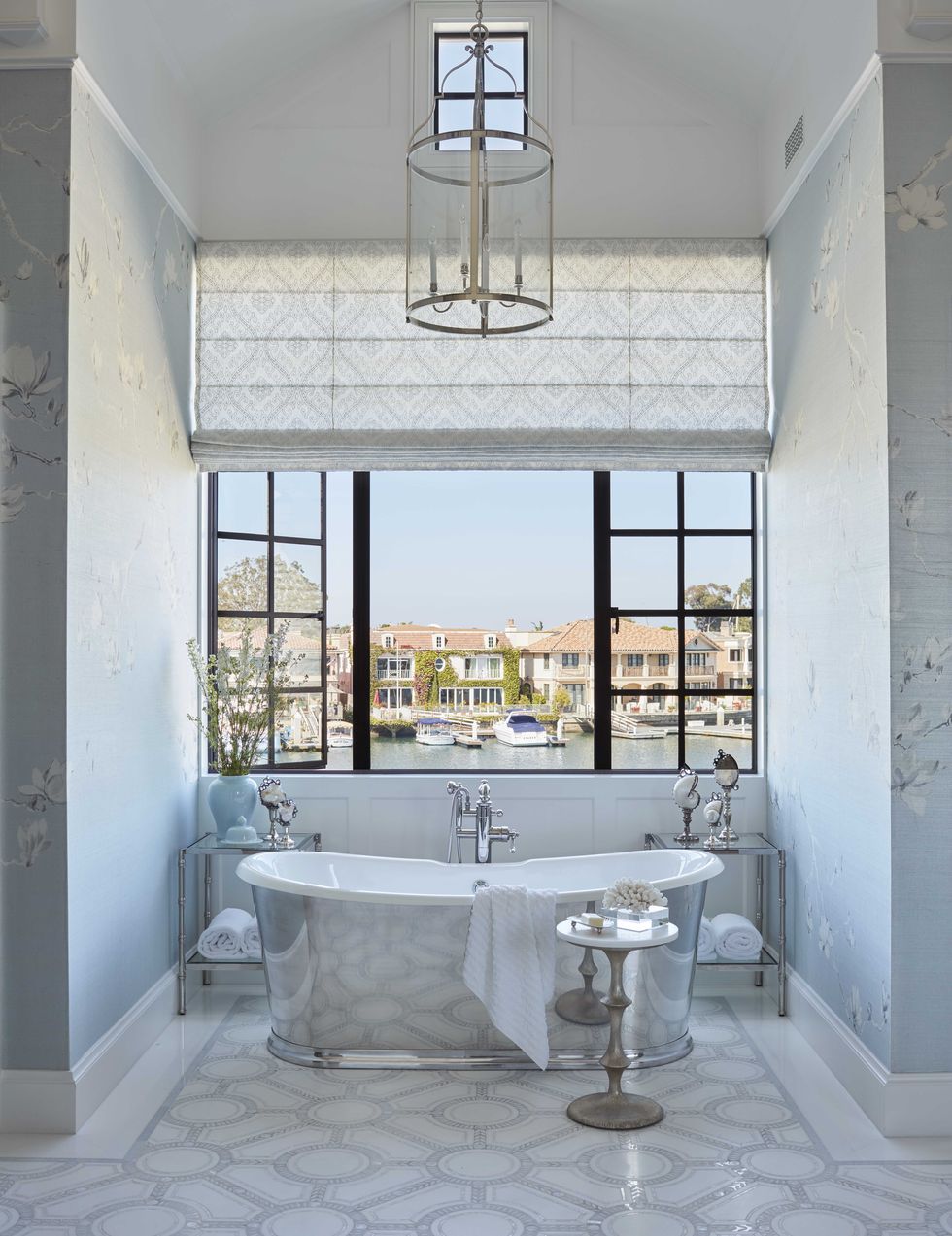 main bathroom, with silver bath tub overlooking views of water, blue wallpaper