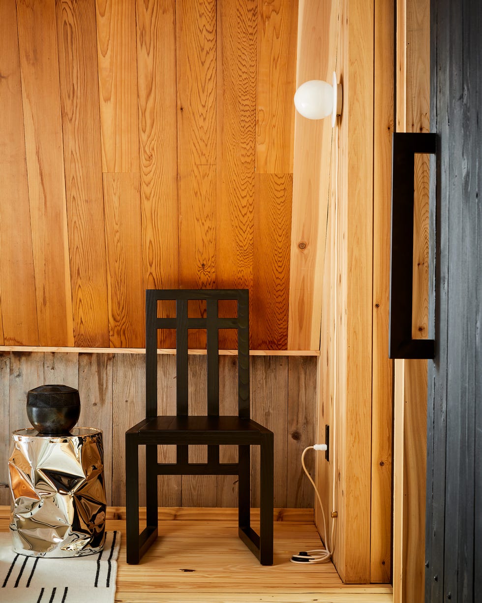 minimalist corner of a room featuring a chair side table and wall lamp