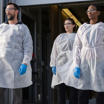 group wearing protective clothing standing at a building entrance group wearing protective clothing standing at a building entrance