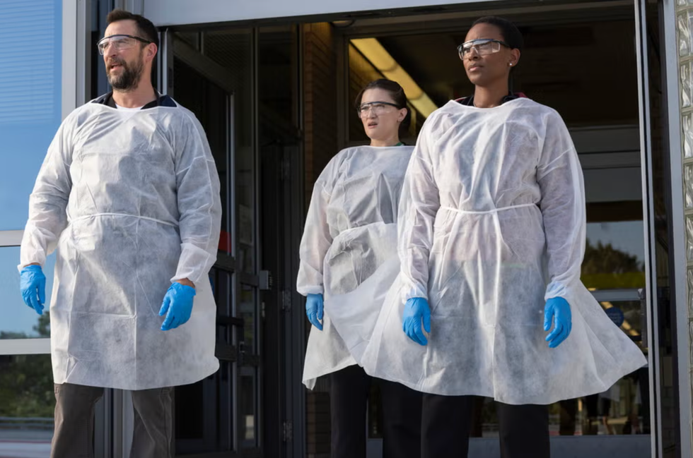 group wearing protective clothing standing at a building entrance