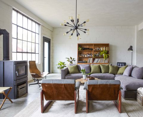 gray sofa, concrete floors, green pillows, wood burning stove
