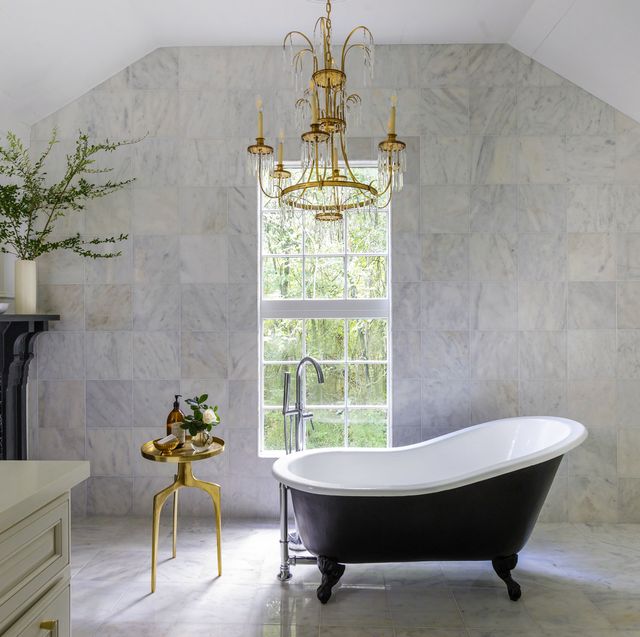 a classic black slipper tub anchors this spacious primary bathroom in the louisiana home of designer krystal matthews chandelier vintage tiles the home depot side table uttermost tub and fittings build with ferguson