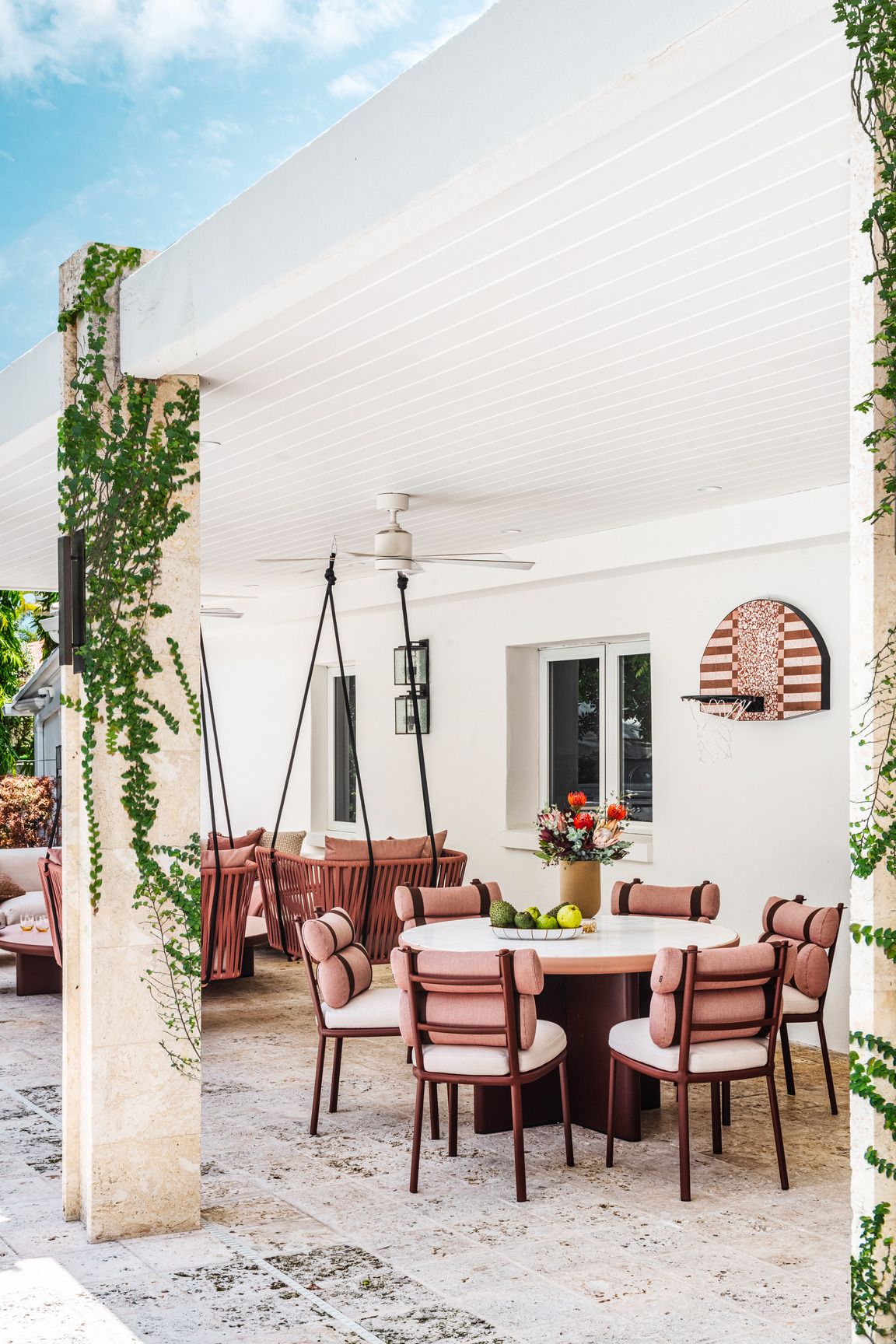 on a limestone patio, moniomi design placed kettal furniture to create a multipurpose area for dining, hanging out, and playing an overhang supported by travertine columns makes it useful in any weather