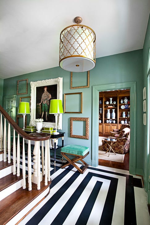 a room with a staircase and a table with a lamp on it