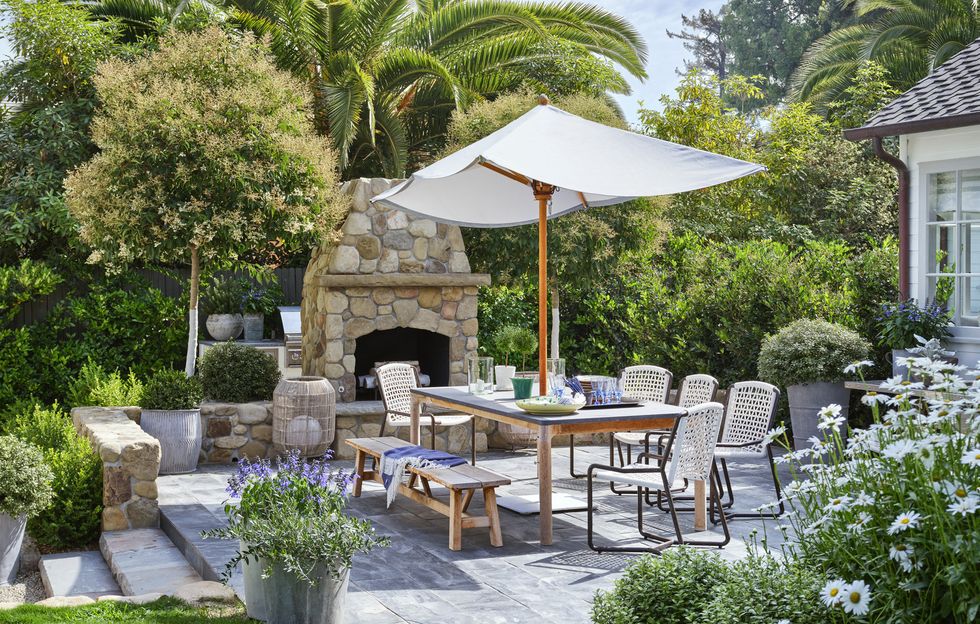 interior designer jeffrey alan marks' american colonial revival home near butterfly beach in montecito, california terrace table and bench david sutherland chairs and floor lamp palecek umbrella santa barbara designs planters pennoyer newman landscaping montecito landscape