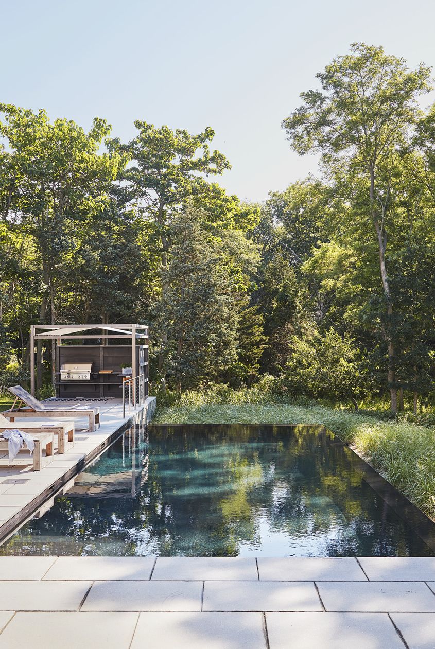 hamptons home designed by pam schneider and architect pospisil brown architects backyard the infinity pool, from rachel lynch swimming pools and spas, seamlessly blends into the surrounding natural landscape chairs bloom sag harbor kitchen wwoo concrete outdoor kitchen