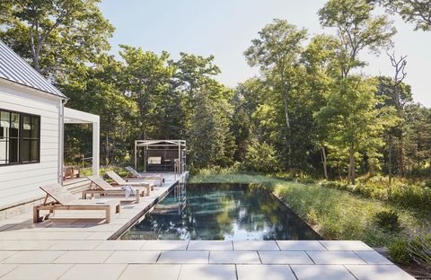 hamptons home designed by pam schneider and architect pospisil brown architects backyard the infinity pool, from rachel lynch swimming pools and spas, seamlessly blends into the surrounding natural landscape chairs bloom sag harbor kitchen wwoo concrete outdoor kitchen