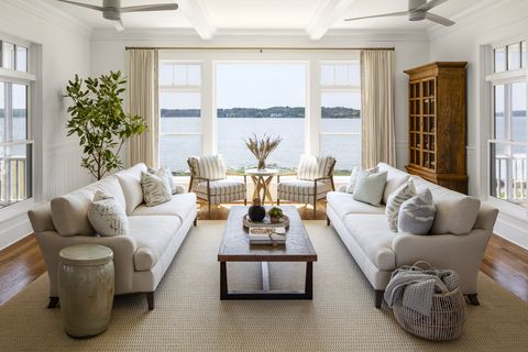 living room low slung sofas by lee industries keep all eyes on the waterfront views in this chesapeake bay house by laura hodges studio sisal rug dash albert coffee table theodore alexander basket and garden stool domain by laura hodges studio cabinet vintage chairs sam moore side table fairfield chair