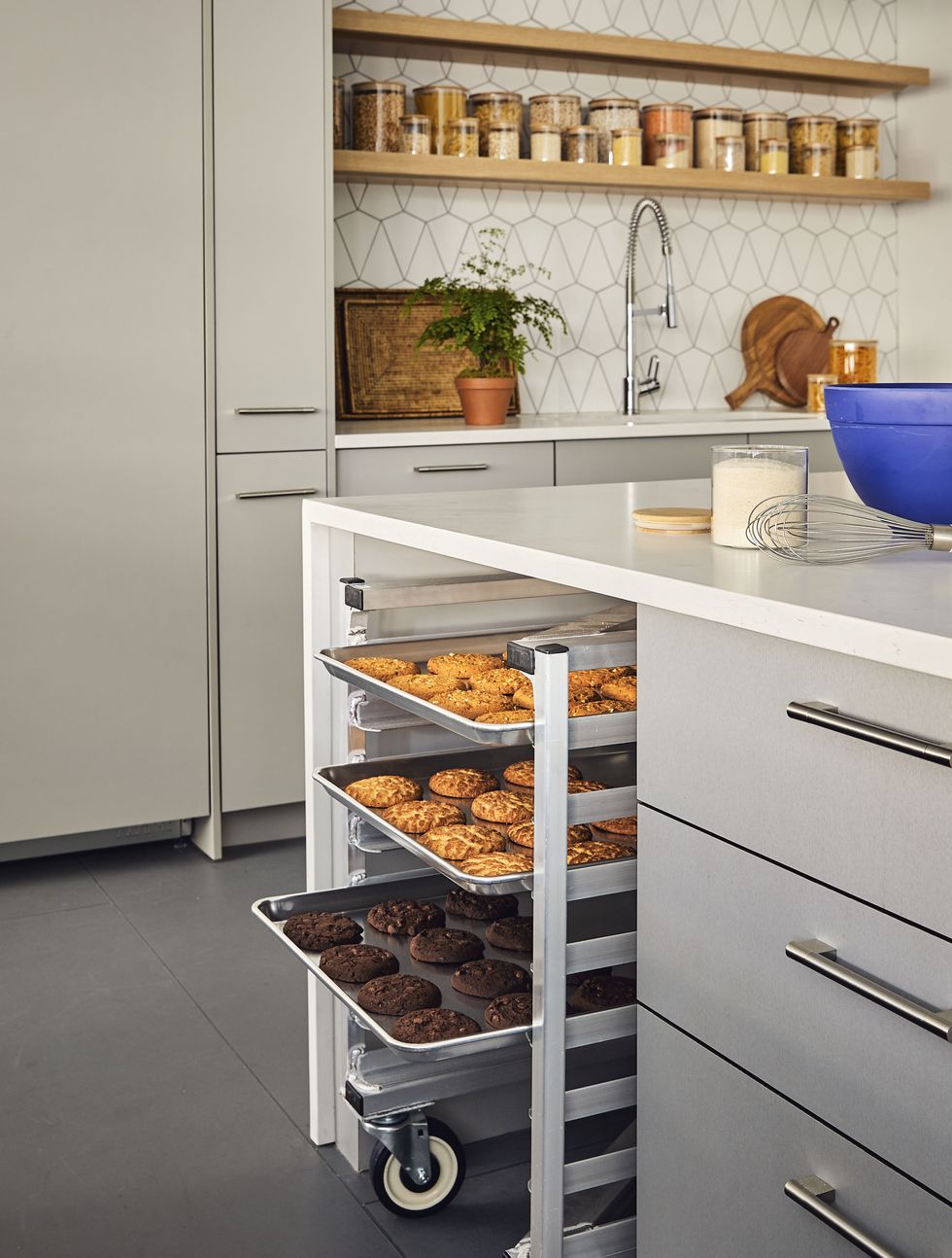 cooling rack with baking sheets full of cookies, tucked away in a kitchen island