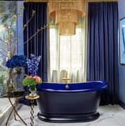 blue bathtub, blue curtains, gold chandelier, floral arraignment