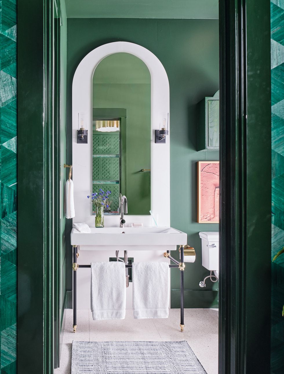 guest bathroom adjoining the main room coated in green paint with mixed brass, black, and polished nickel, and an arched backsplash and mirror behind the console sink fixtures signature hardware towels tencel,