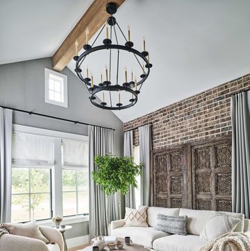 owners den, brick wall, white lounge sofa, white lounge chairs, throw rug, white and cream decorative cushions, gray walls, gray curtains, black candle ceiling light