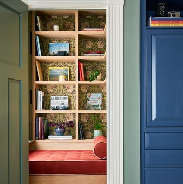 a closet with a door and books on the shelves