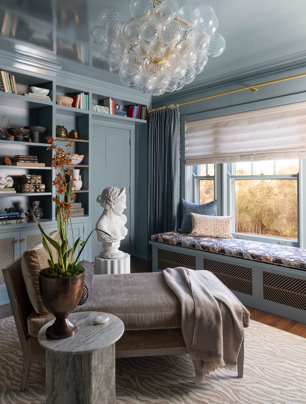 a living room with a statue and a shelf with books