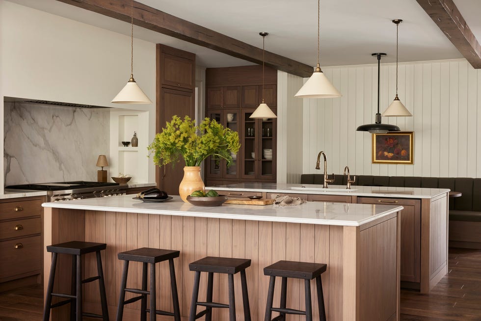 kitchen the double islands maximize prep space cabinetry, hardware, and pendants white devol stools black creek mercantile  trading co faucet brizo lamp dumais made backsplash, counters calacatta marble quiet time warm tones and natural textures took this indiana home from cavernous to cozy warm neutrals, williams creek, indiana, georgian style residence, natural materials, wood accents