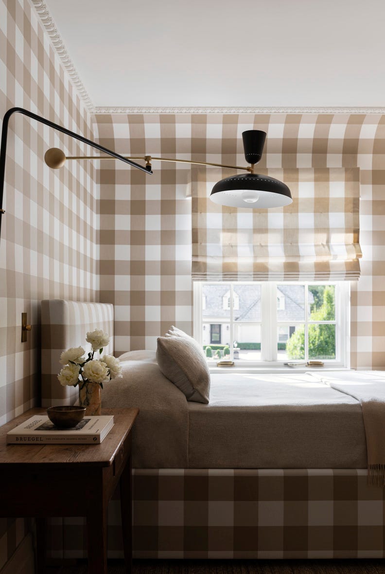 hold the line: elegant design, neutral color palette. chicago home designed by wendy labrum with michael abraham architecture. inspiration: english country estate with a contemporary twist. guest bedroom using a single fabricut fabric on the walls, bed, and shade “added a bit of traditional whimsy in an impactful way,” labrum says. the contemporary pierre guariche wall lamp enlivens the space.