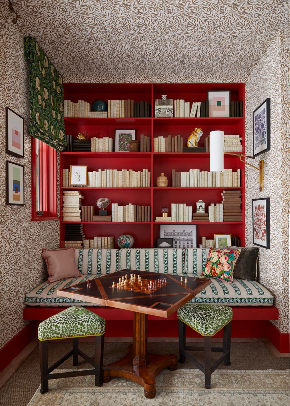 game room: ma allen interiors maalleninteriors. morris co. botanical motif on the walls and ceiling and red trim. spare guest room\, lounge\, living room. bench slash daybed and bookcase for the alcove\, cheeky animal print stools\, and bespoke daybed\, eye catching textiles. a round pedestal table opens up to a game table for four. daybed cushion: custom\, in morris co. fabric. sconce: visual comfort co. stools: lee industries. paint: romesco\, farrow ball. books: sarreid ltd. art: baumbirdy\, jessica c. nugent\, katharine watson\, shina choi\, all from minted. whole home 2024. this year energy efficient home is in the conservation minded community of sprout\, located on a private nature preserve in hendersonville\, north carolina.