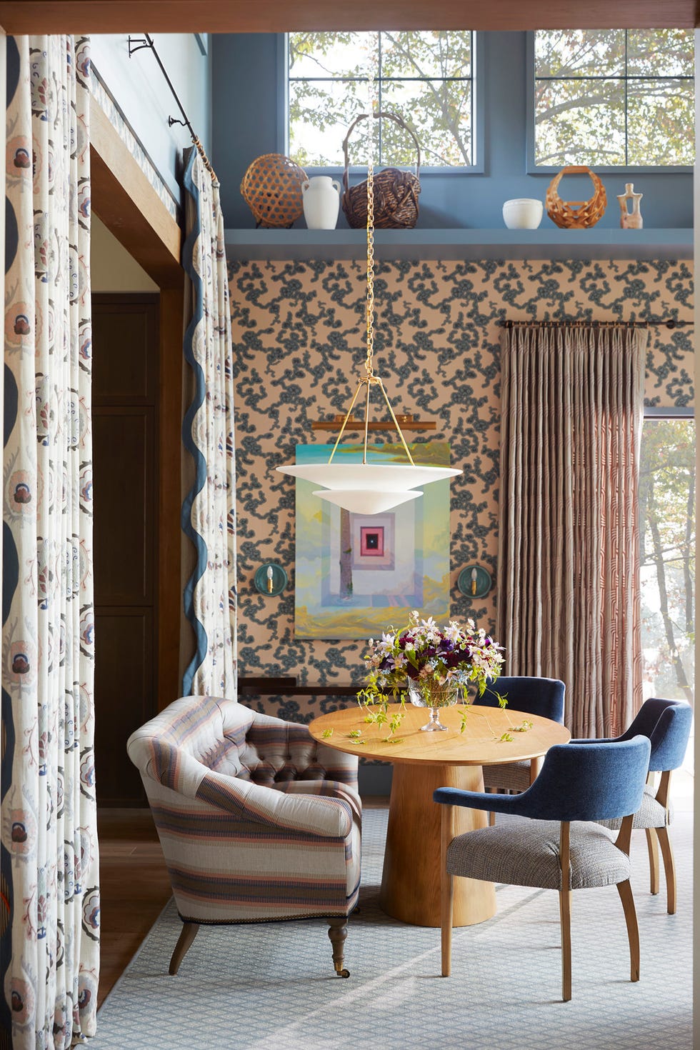 the living dining room: by dane austin design daneaustindesign. floor to ceiling chimney breast\, constructed with cosentino dekton ultracompact surface material. a farrow ball cherry blossom–inspired wallpaper (reproduced from a design discovered in an 18th century château) is a stunning backdrop. blue walls. dining area a plaster finished visual comfort co. pendant hangs low over the table. table: wayfair professional. drapery fabric: sanderson.whole home 2024. this year energy efficient home is in the conservation minded community of sprout\, located on a private nature preserve in hendersonville\, north carolina. living room, dining room.