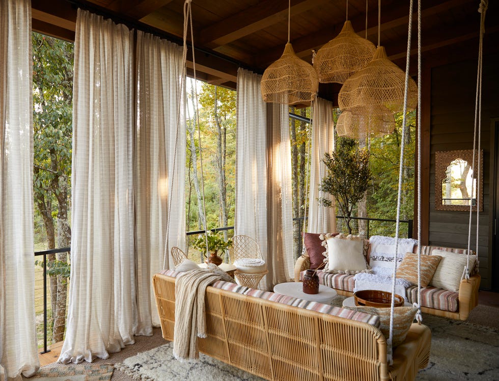 outdoor spaces: curated nest @curatednest, lina galvão and her partner erin coren. upper patio: hanging daybeds from serena  lily get a dramatic makeover in a rose stripe cover in fabricut fabric and ample pillows. mirror: wayfair professional. chairs: vintage. pillow fabrics: vervain, fabricut, s. harris. drapery fabric: stroheim. deck, outdoor living. whole home 2024. this year’s energy efficient home is in the conservation minded community of sprout\, located on a private nature preserve in hendersonville\, north carolina.