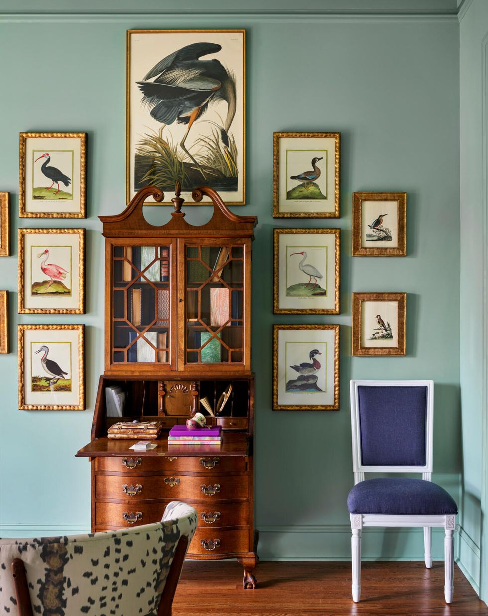 a wooden secretary desk and gallery wall with bird artwork