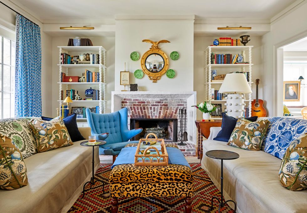tall book shelves, fireplace, tan seating, and an animal print ottoman