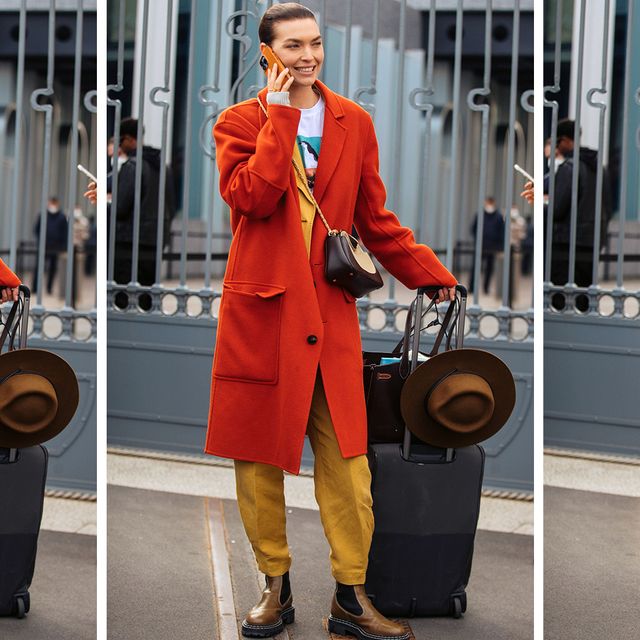 a model stands with a suitcase and bags to illustrate a guide to the best garment bags 2022