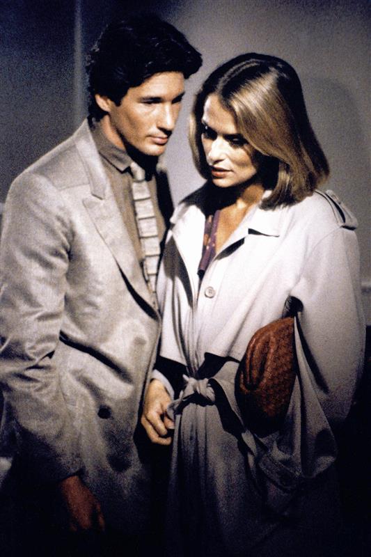 a couple in formal attire standing closely together in a muted indoor setting