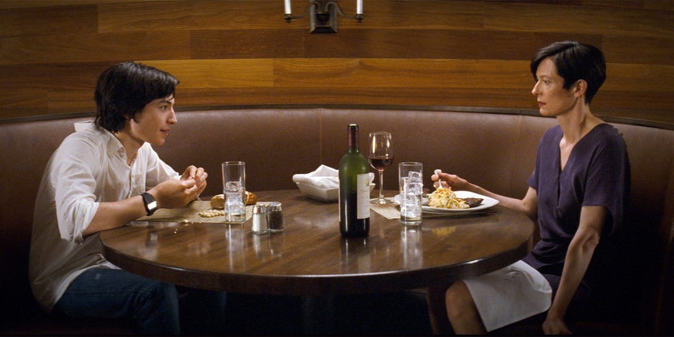 dinner setting with two people at a round table featuring food and drinks