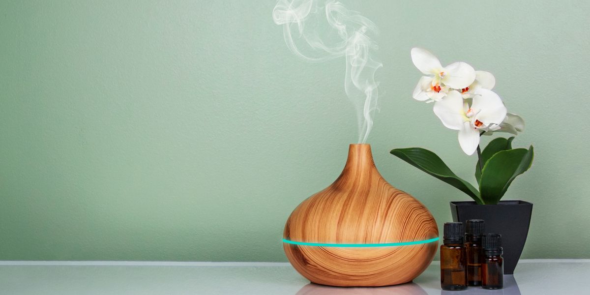 electric essential oils aroma diffuser, oil bottles and flowers on light green surface with reflection shutterstock id 1276273048 purchase order