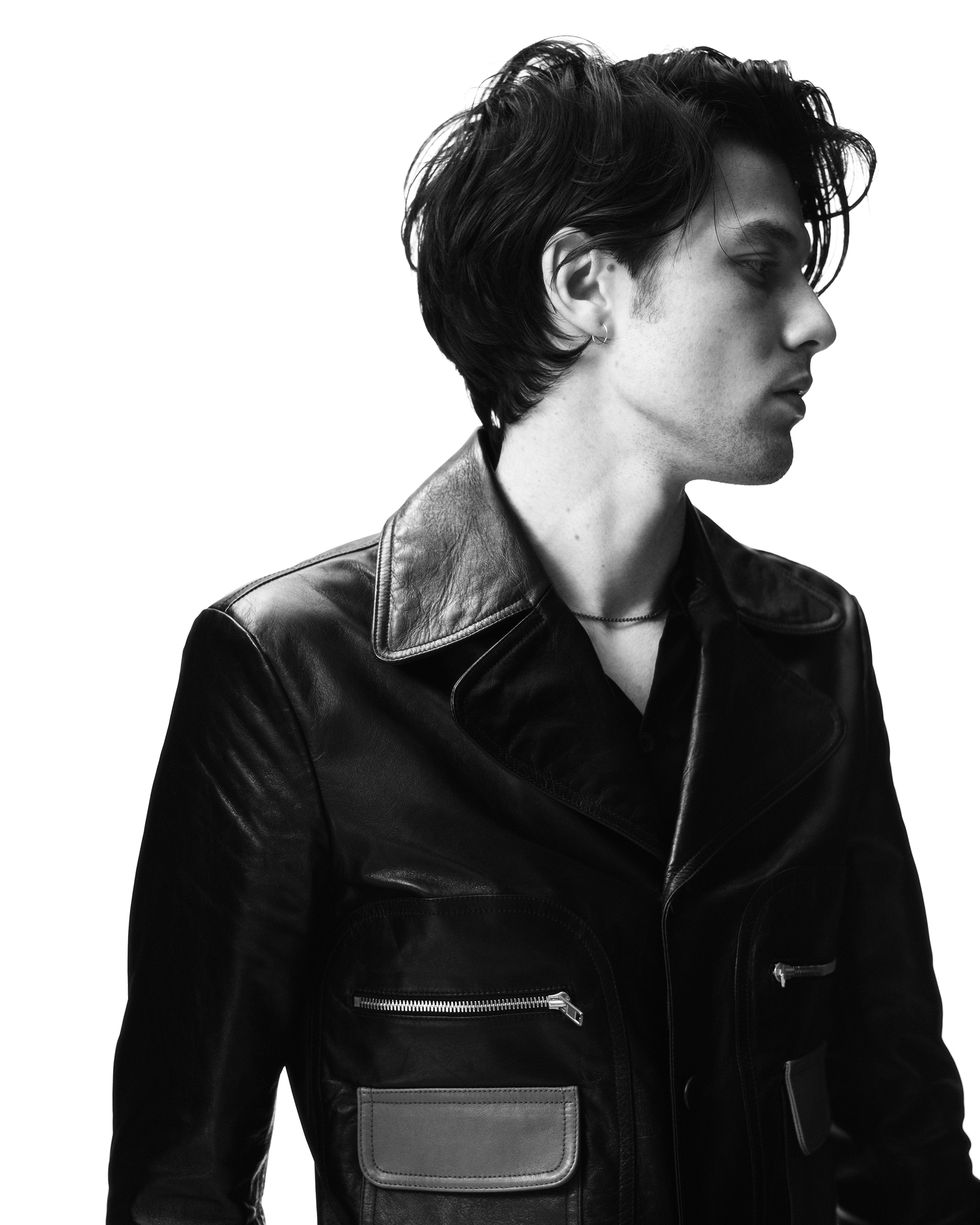 Hair, Black, Leather, Jacket, Leather jacket, Hairstyle, Beauty, Neck, Standing, Black-and-white, 