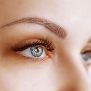 Eyelash Extension Procedure. Woman Eye with Long Eyelashes. Close up, selective focus