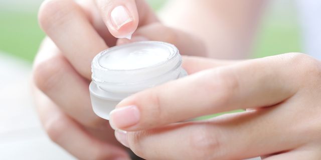Hand of woman holding moisturizer cream and serum. She applying a facial cream , essential , oil , lotion and body cream for skin care, close up view and blur background. Beauty and Healthy Concept.