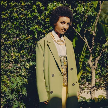 model wearing a green oversized coat and a yellow skirt in a lush outdoor setting model wearing a green oversized coat and a yellow skirt in a lush outdoor setting