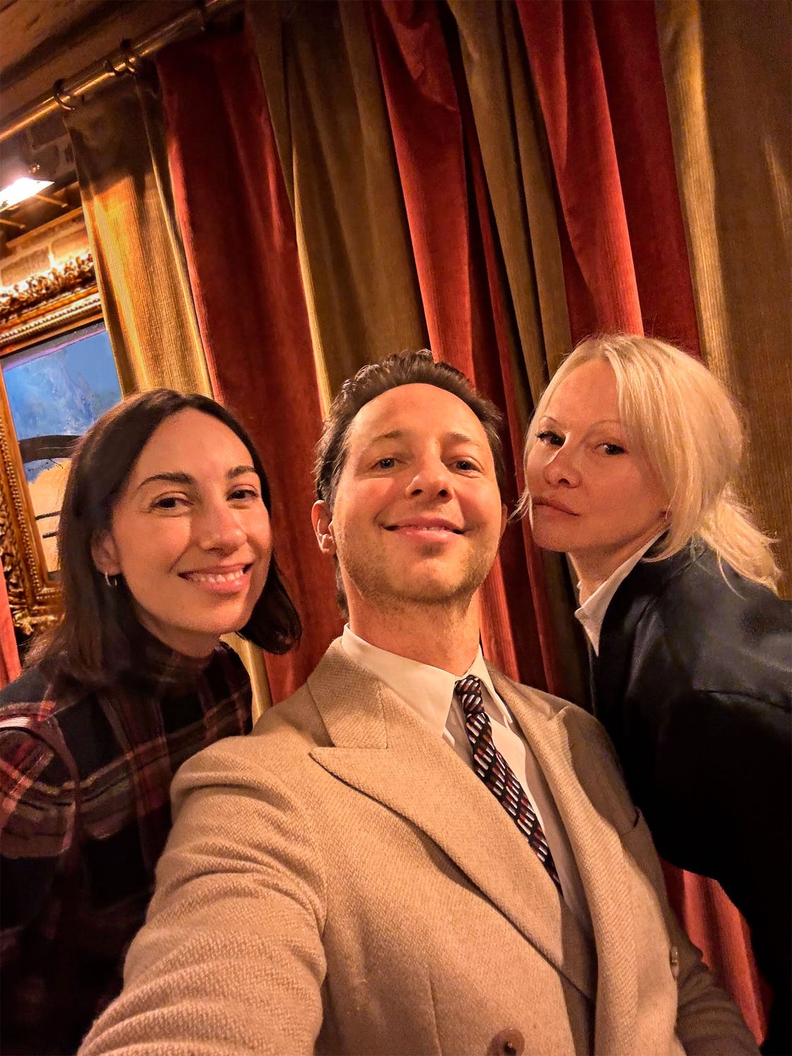 group selfie taken indoors with colorful drapes and artwork in the background