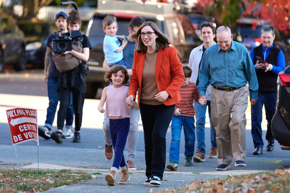 Group of adults and children walking towards a polling place