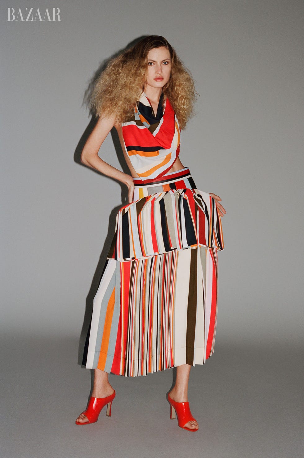 model showcasing a fashionable dress with bold stripes and red highheeled shoes